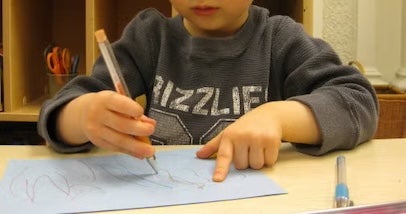 child drawing on a blue piece of paper
