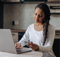 A woman holding a credit card and typing into a laptop computer.