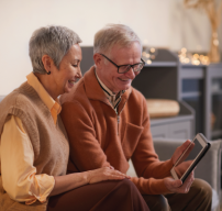 A couple of retirement age both looking at a tablet screen and smiling